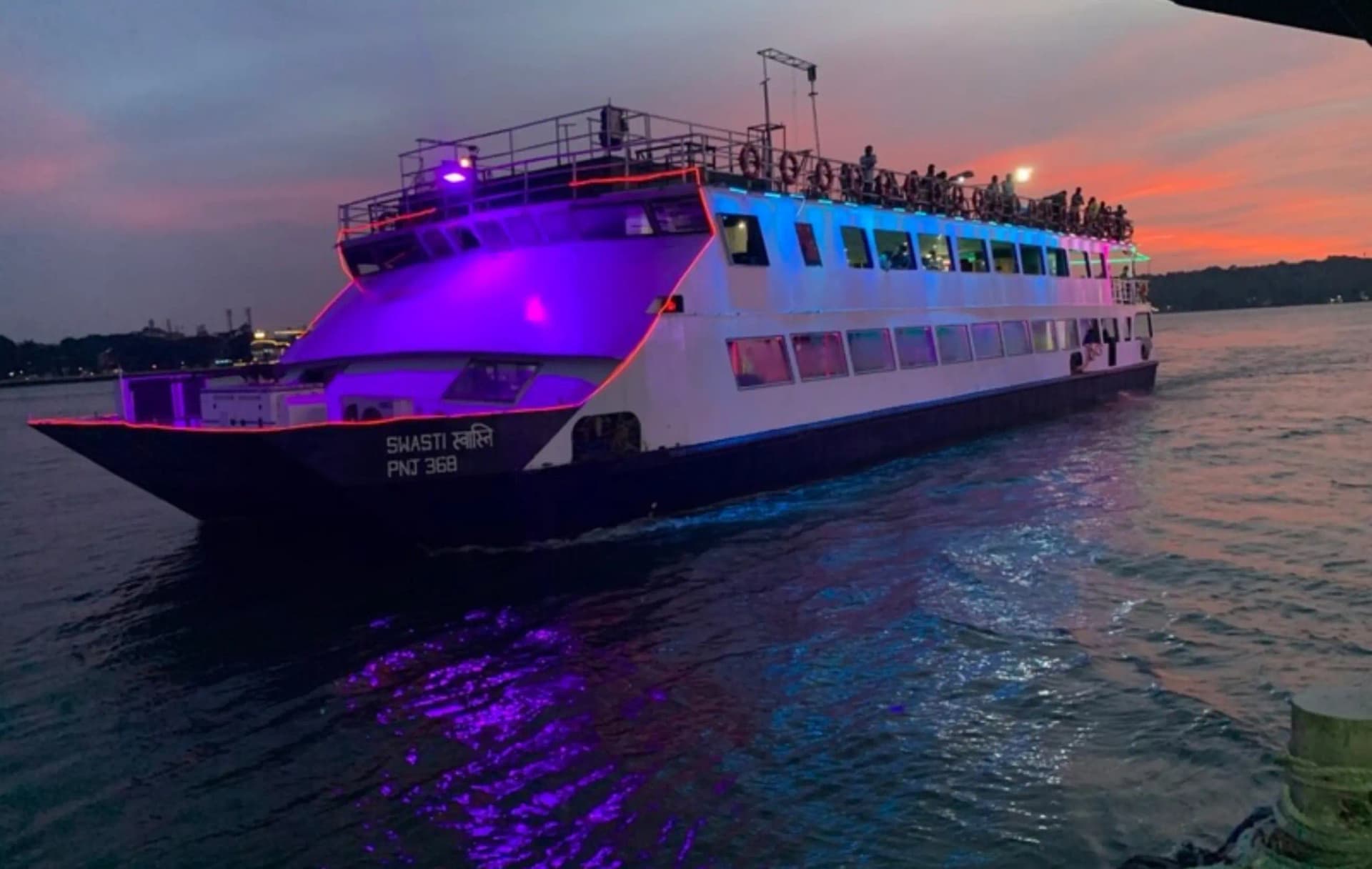 Cruise boat with purple deck lights at sunset
